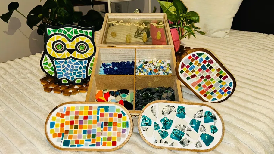 Mosaikkunstwerke mit bunten Fliesen auf Tisch.