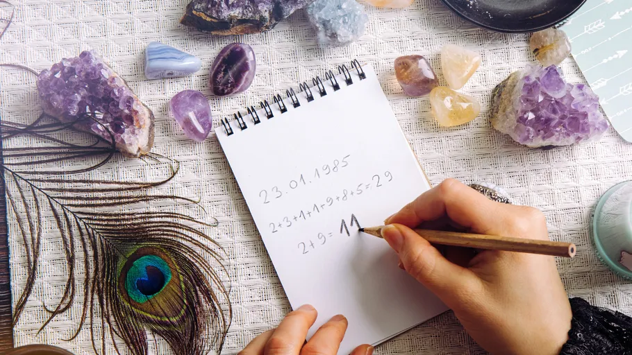 Hands writing on notepad surrounded by crystals.