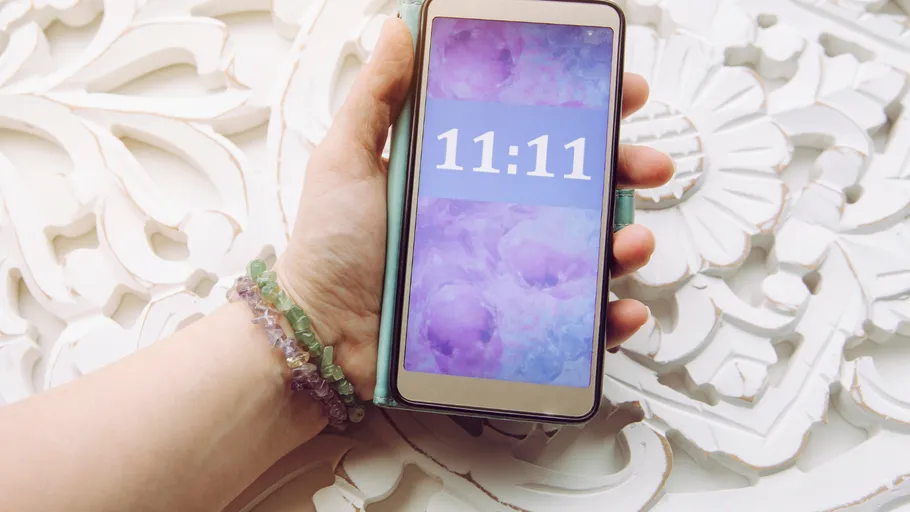 Hand holds smartphone displaying 11:11 on screen.