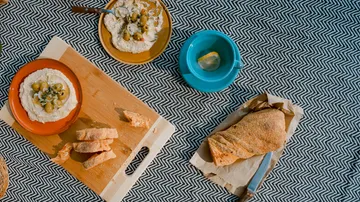 Plates of dip, bread, and tea on a tablecloth.