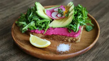 Avocado toast with pink spread and greens.