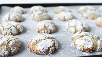 Powdered sugar cookies on a baking sheet.