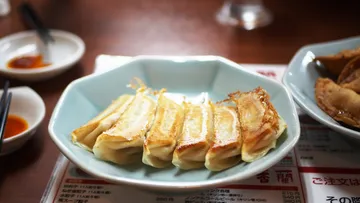 Plate of gyoza with sauce and menu.
