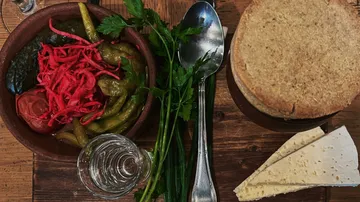 Brot, Käse und Gurken auf Holztisch.