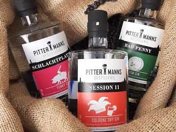 Drei Gin-Flaschen liegen in einem jutesack.