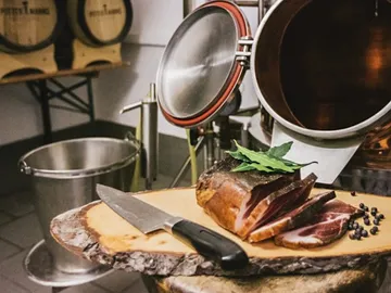 Holztisch mit geschnittenem Fleisch, daneben eine Klinge, in einer Küche.