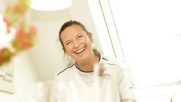 Frau lächelt drinnen, sanft beleuchteter Raum.
