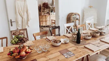 Dining table set with fruits, drinks, and decorations.