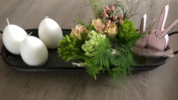 Tray with candles and floral arrangement on table.