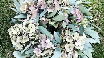 Floral wreath with hydrangeas on grass.
