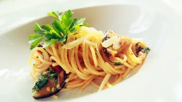 Spaghetti with herbs and vegetables on plate.