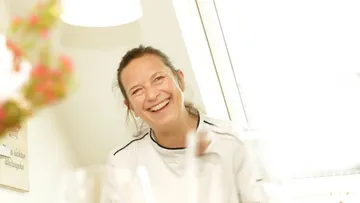 Smiling woman in white indoors, bright room.