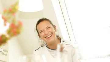 Lächelnde Frau in hellem, weißen Raum.