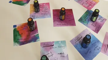 Ätherische Ölflaschen auf bunten Notizen, weiße Oberfläche.