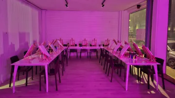 Staffeleien in einem pink beleuchteten Raum.