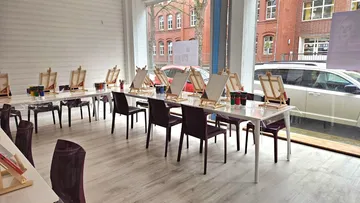 Leeres Atelier mit Staffeleien und Stühlen.