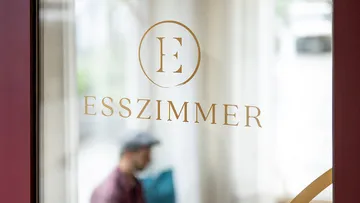Glastür mit 'ESSZIMMER' Text, unscharfer Hintergrund.