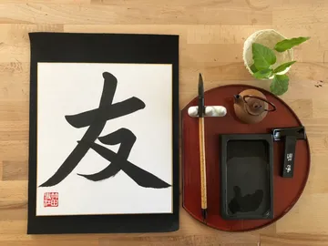 Ink, brush, and characters on a wooden background.
