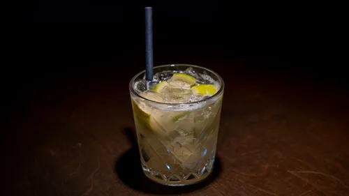 Cocktailglas mit Strohhalm auf dunklem Tisch.