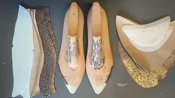 Schuhleisten und Stoffstücke auf Tisch.