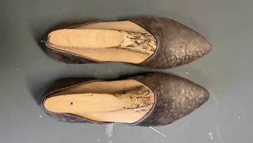 Old shoes with wooden block inserts, gray floor.