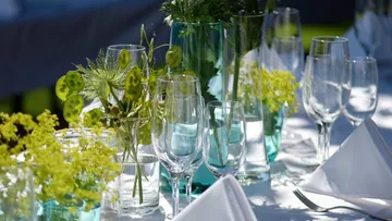 Glasses and flowers on elegantly set table.