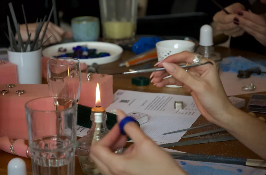 Hände basteln Schmuck mit Werkzeugen auf Tisch.