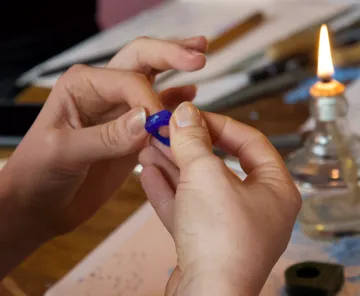 Hands holding a blue ring near a flame.