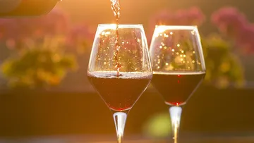 Wine poured into glasses at sunset.