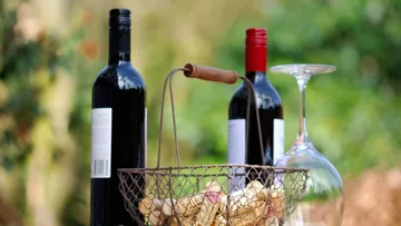 Wine bottles and corks in a basket, outdoors.