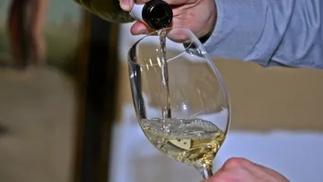 White wine poured into glass by hand.