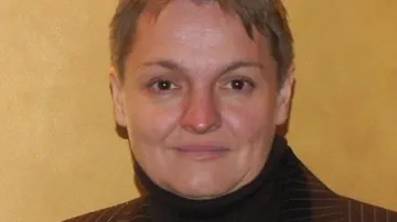 Person lächelt vor einfachem Hintergrund.