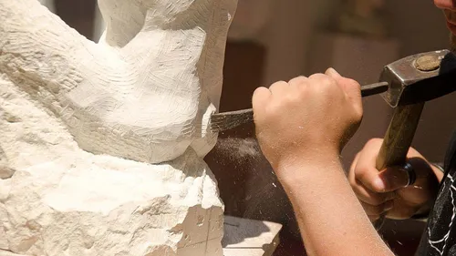Hand carving stone sculpture with chisel.