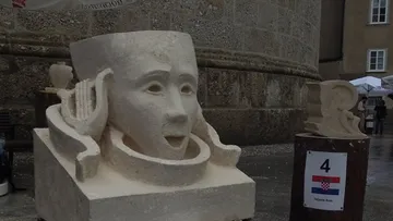 Abstract face sculpture outside historical building.