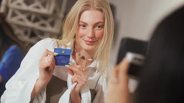 Woman holding jewelry box, smiling indoors.