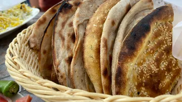 Basket filled with naan bread outdoors.