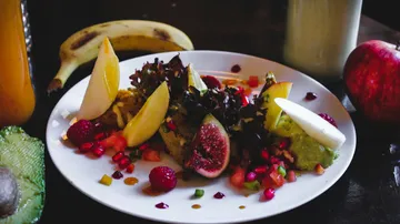 Fruit and salad arrangement on white plate.