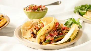 Gemüsetacos auf Teller mit Salsa-Schale.