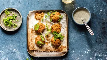 Falafel mit Koriander auf Tablett, Sauce daneben.