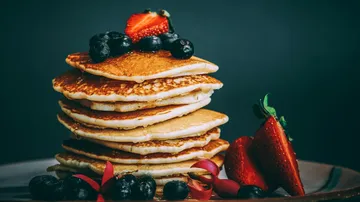Stapel Pfannkuchen mit Beeren auf Teller.