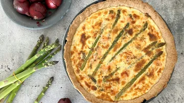 Spargelquiche mit Zwiebeln und Spargel in der Nähe.