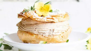 Pastry with cream, yellow flower garnish.