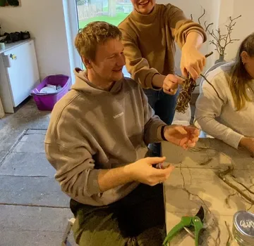 Menschen basteln mit Zweigen drinnen.