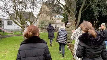 Group of people walking in a garden.