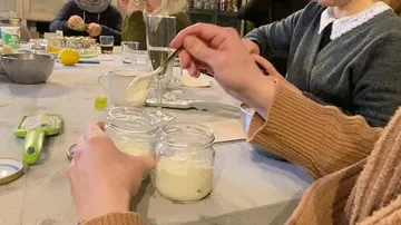 People preparing jars of yogurt at a table.