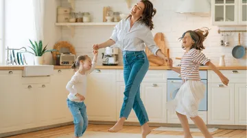 Family joyfully dancing in bright kitchen.
