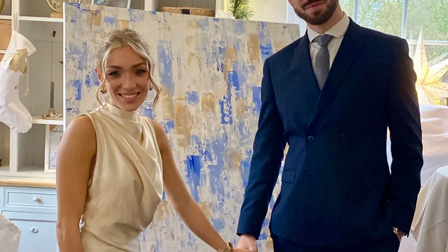 Smiling couple posing in front of abstract painting.