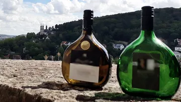 Zwei Weinflaschen auf Steinmauer, malerischer Hintergrund.