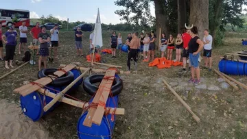 Group building homemade rafts near trees.