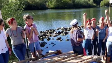 Group of women celebrating on a riverbank.
